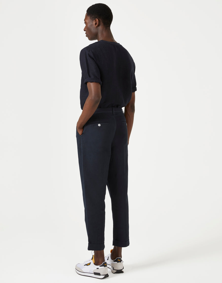 Model wearing men's dark navy short sleeve t-shirt and casual trousers, view from the back